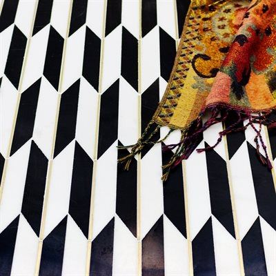 Black and white geometric tile background with a colorful patterned scarf draped across it.