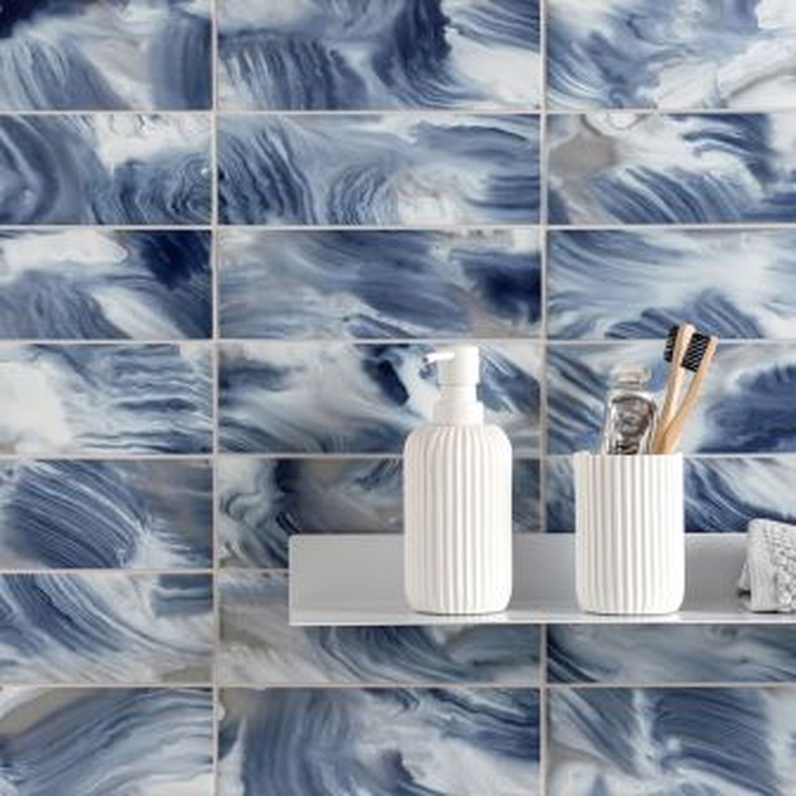 Blue and white marbled ceramic tile bathroom wall with a shelf holding toiletries.