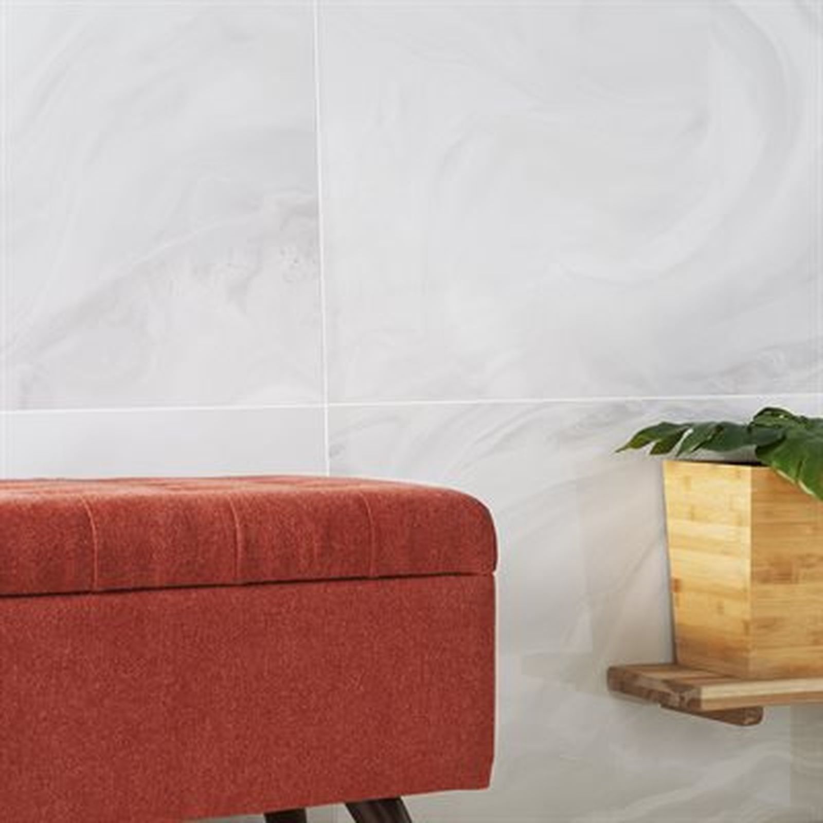 Red bench against a white swirling wall. Plant in a wooden pot sits on a wooden shelf.