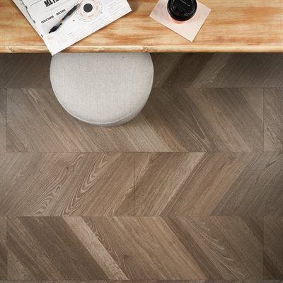 Overhead view of a wooden desk with a white chair. Wooden chevron patterned floor.