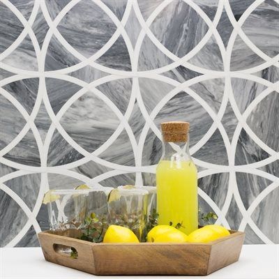 Tray with lemons, glasses, and a carafe of yellow liquid in front of a decorative, patterned tile wall.