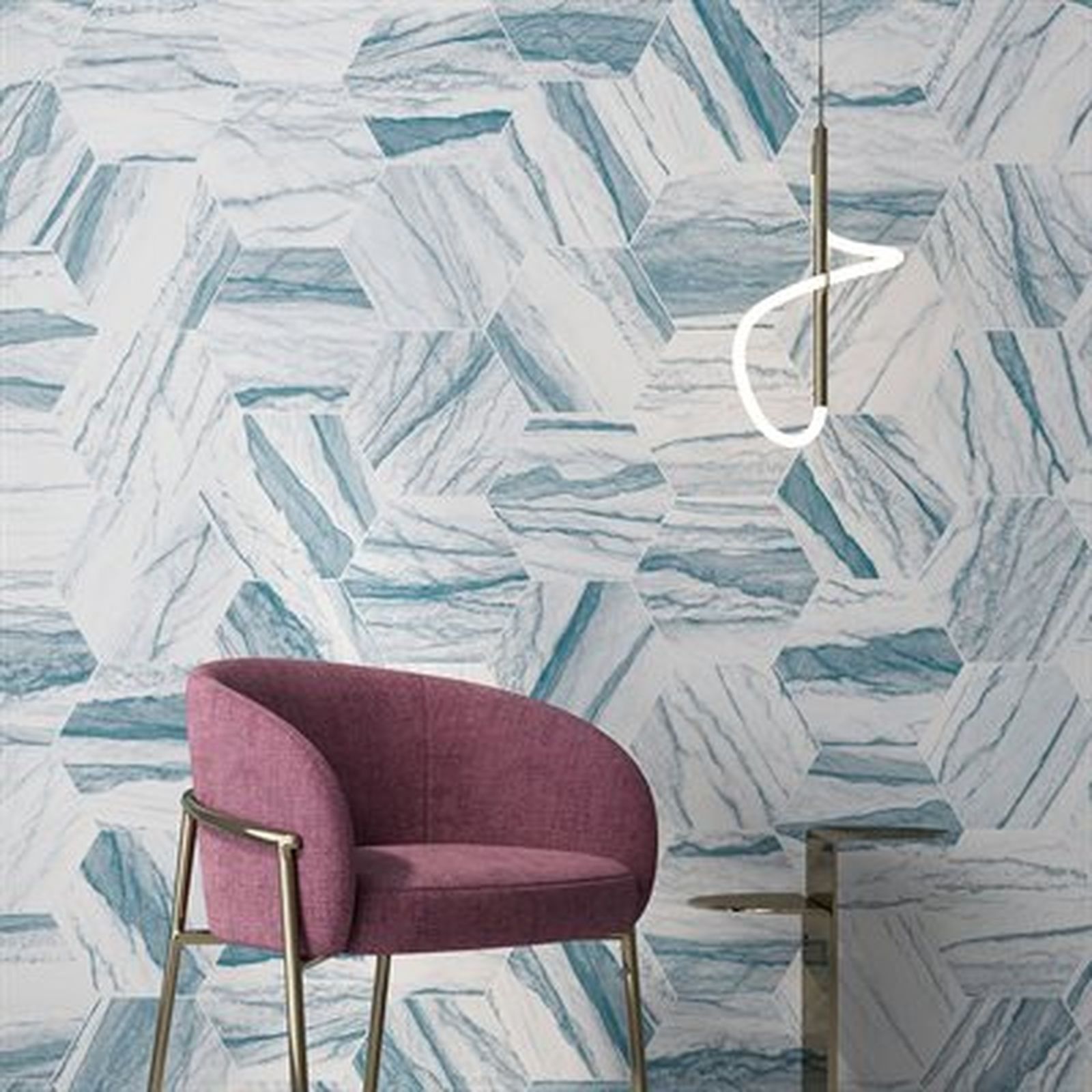 Pink chair in front of a wall with blue hexagonal marble tiles, with a hanging light and small table.