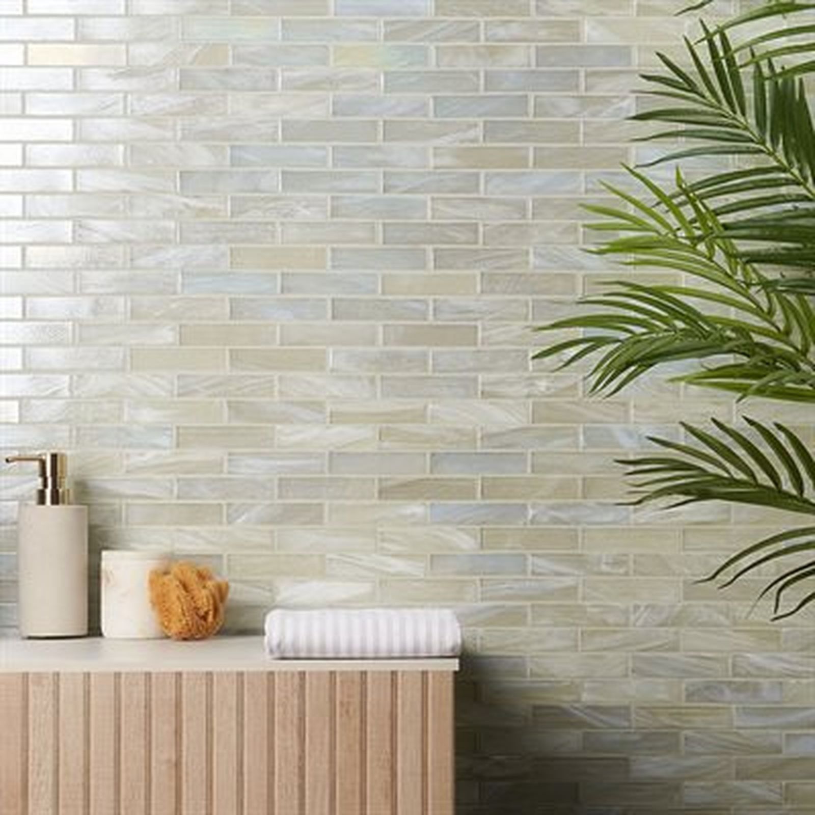 Bathroom with iridescent brick tile, tan cabinet, and green plant.
