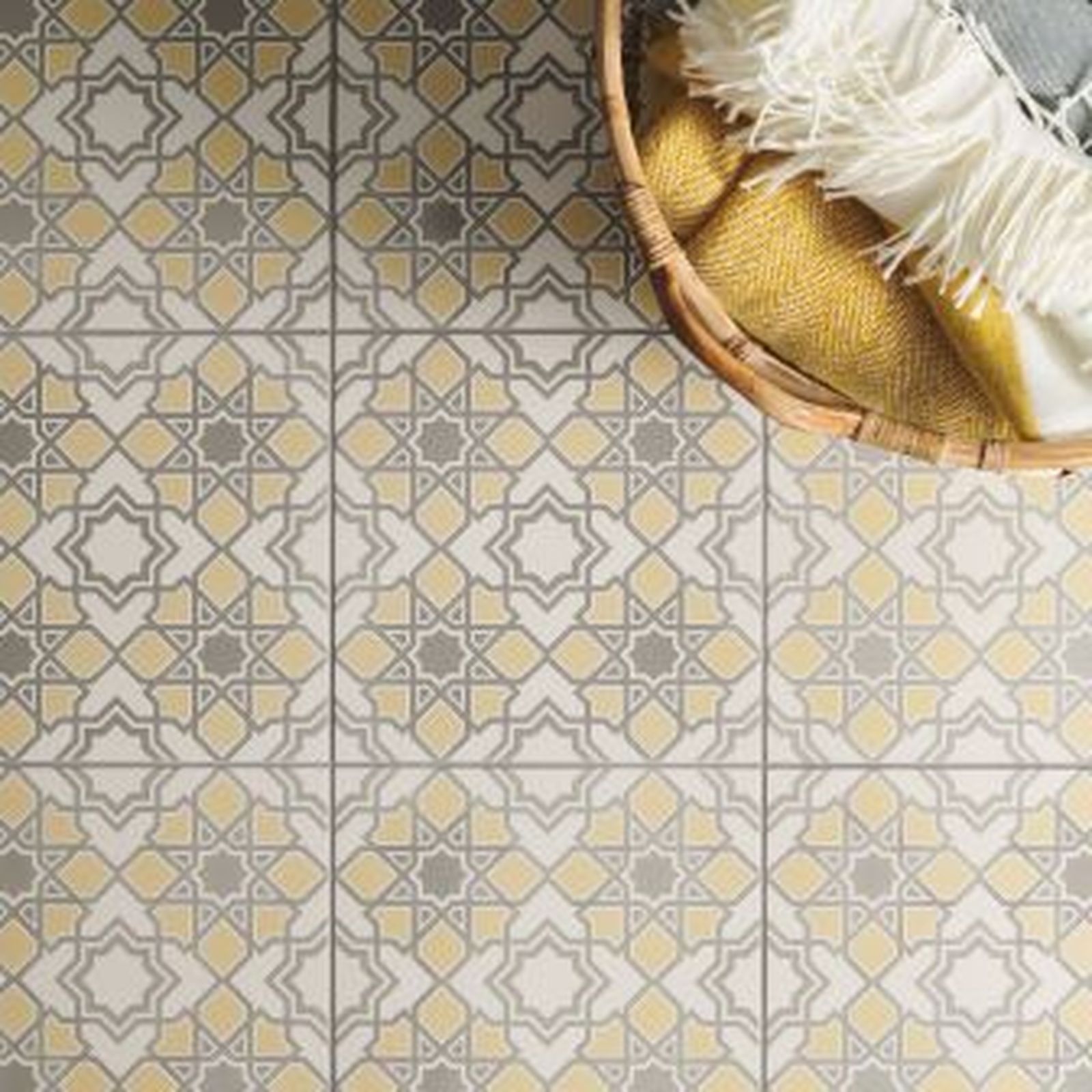 Decorative tile floor with gray and yellow geometric patterns, basket with blanket.