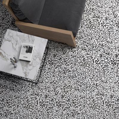 Overhead shot: Armchair and marble coffee table on a speckled black and white floor.