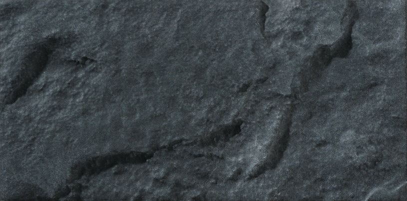 Close-up of a dark, textured stone surface with varying depths and subtle highlights.