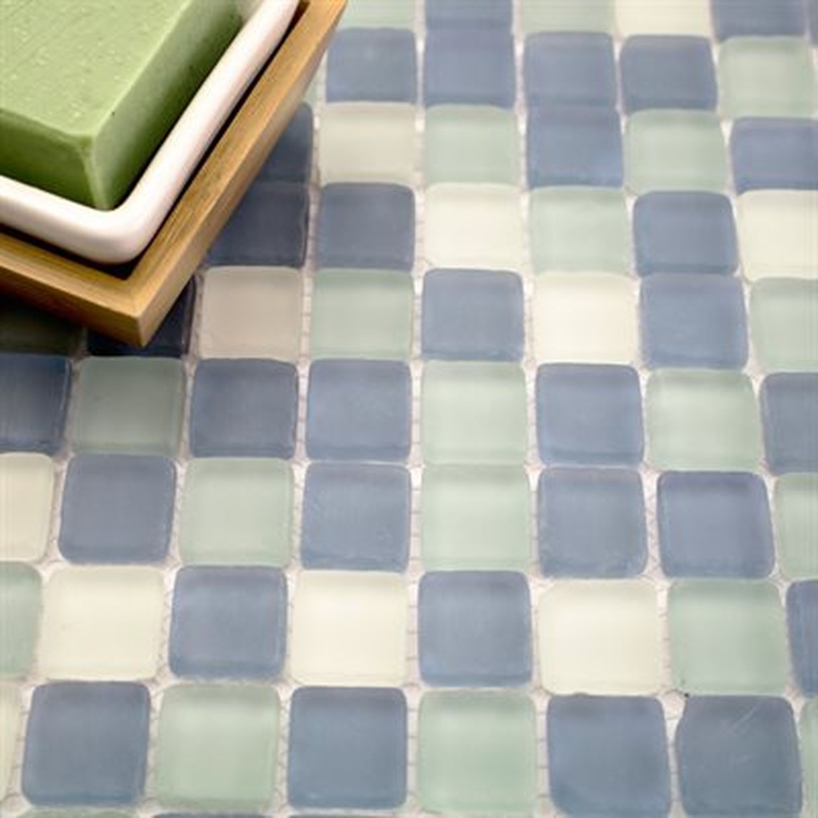 Soap on a wooden tray rests on a mosaic tile surface in shades of blue, green, and white.