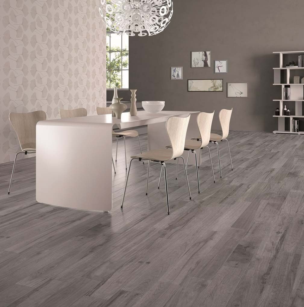 Dining room with white table, chairs, gray wood floor, light gray wallpaper, and decorative chandelier.
