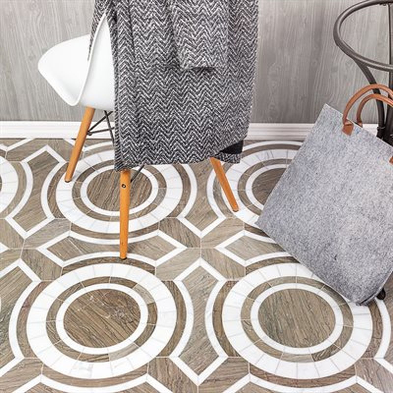 Floor with geometric tile pattern, chair, blanket, and tote bag.