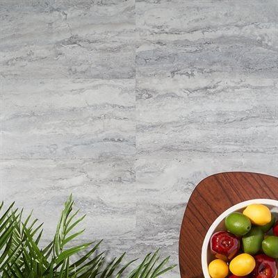 Marble-look tile background with a bowl of fruit and green foliage.