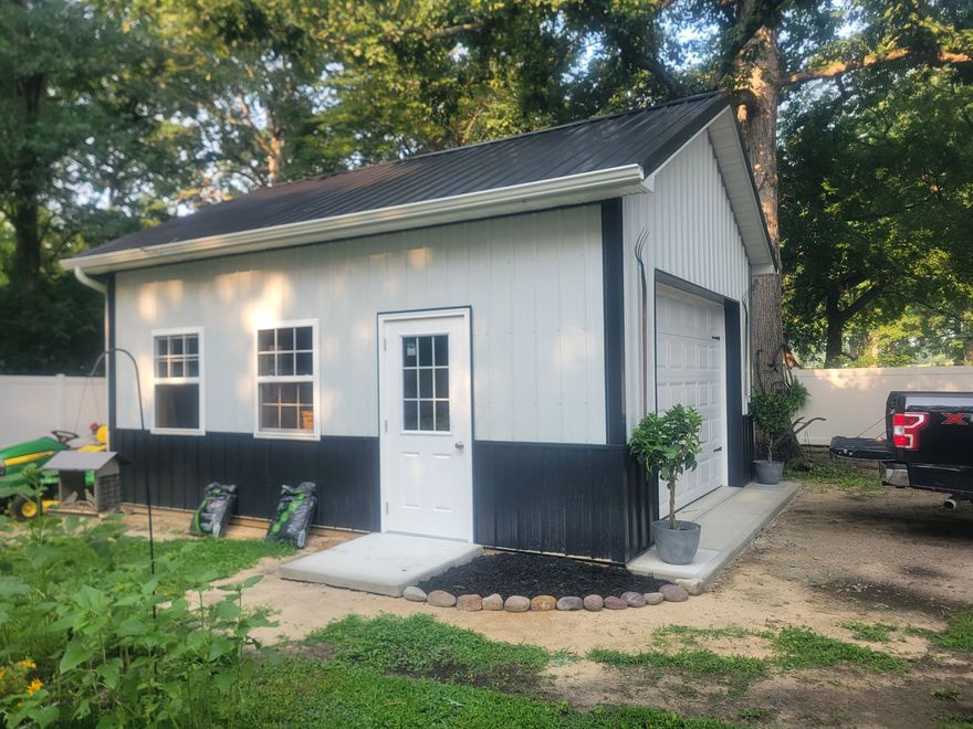 White three-bay garage with light gray trim and a concrete driveway on a sunny day
