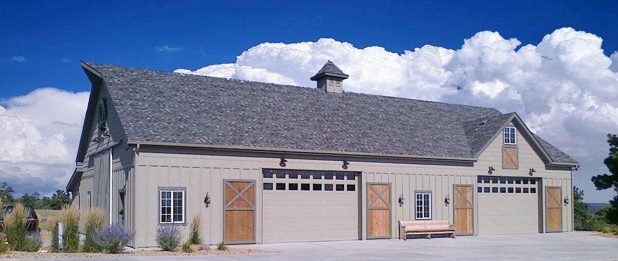 Single-story beige house with a gray roof, two garage doors, and a bench in front
