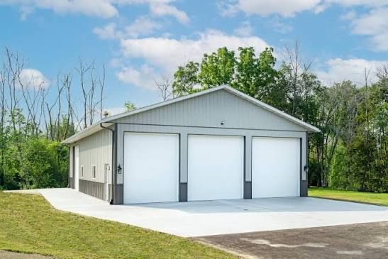 White three-bay garage with light gray trim and a concrete driveway on a sunny day