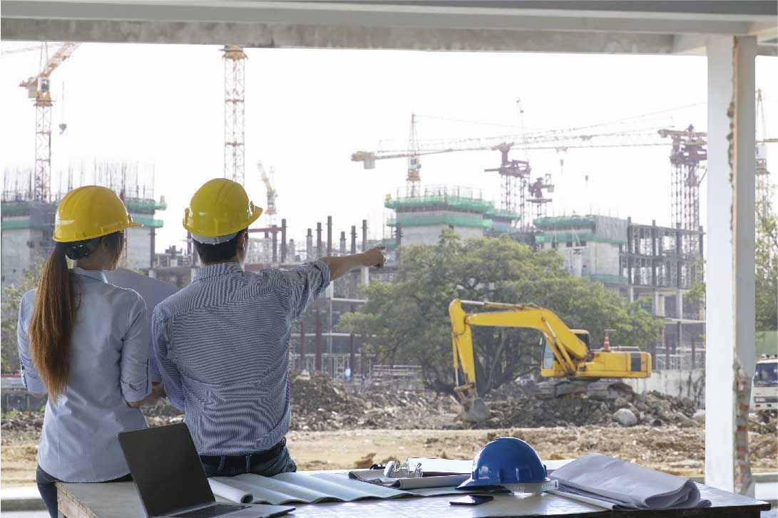 Un hombre y una mujer miran por una ventana una obra en construcción.