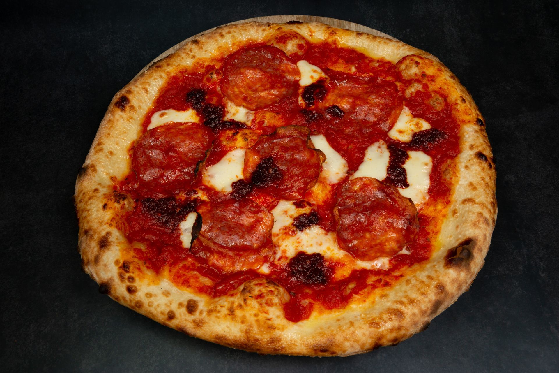 Pizza pepperoni avec fromage fondu sur une surface foncée