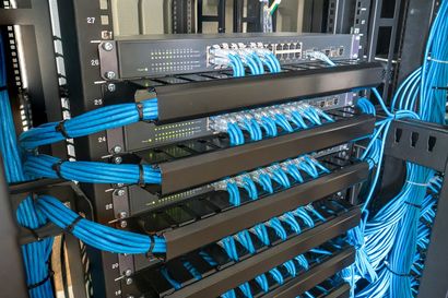 A server rack filled with networking equipment, featuring organized blue Ethernet cables connected to multiple switches.