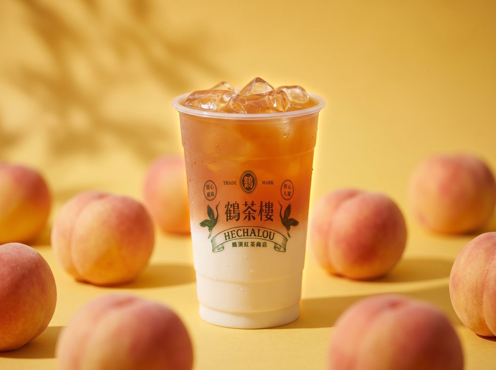 Iced peach tea in a clear cup, surrounded by peaches on a warm yellow background.