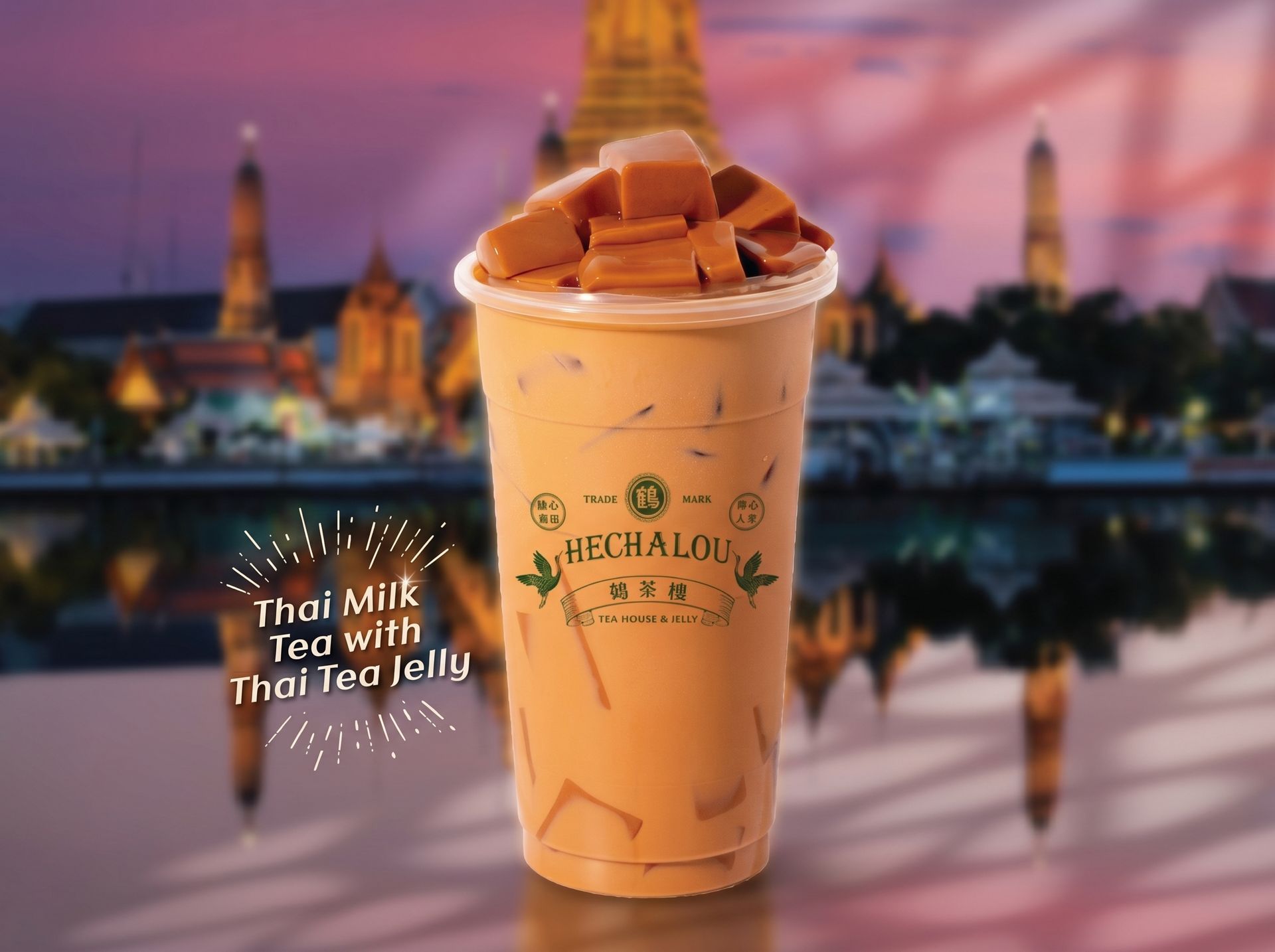 Thai tea milk tea with Thai tea jelly in a clear cup, topped with foam, against a sunset temple backdrop