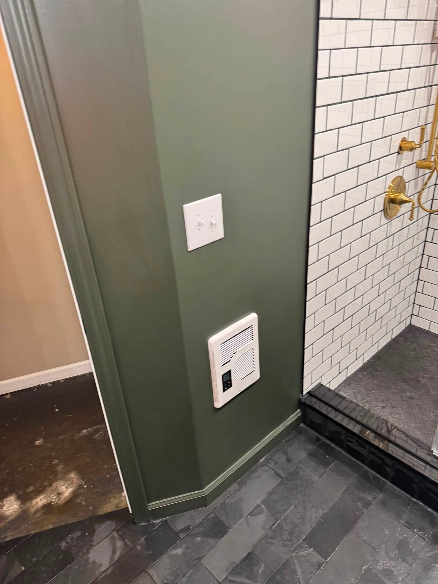 Hallway corner with green wall, white vent and switch, leading to a tiled bathroom shower area