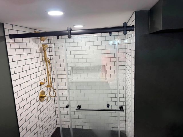 Modern bathroom with white subway tiles, black shower fixtures, and a glass shower enclosure