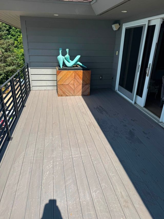 Balcony with gray siding, sliding doors, and a wooden box topped with turquoise decorative figures.