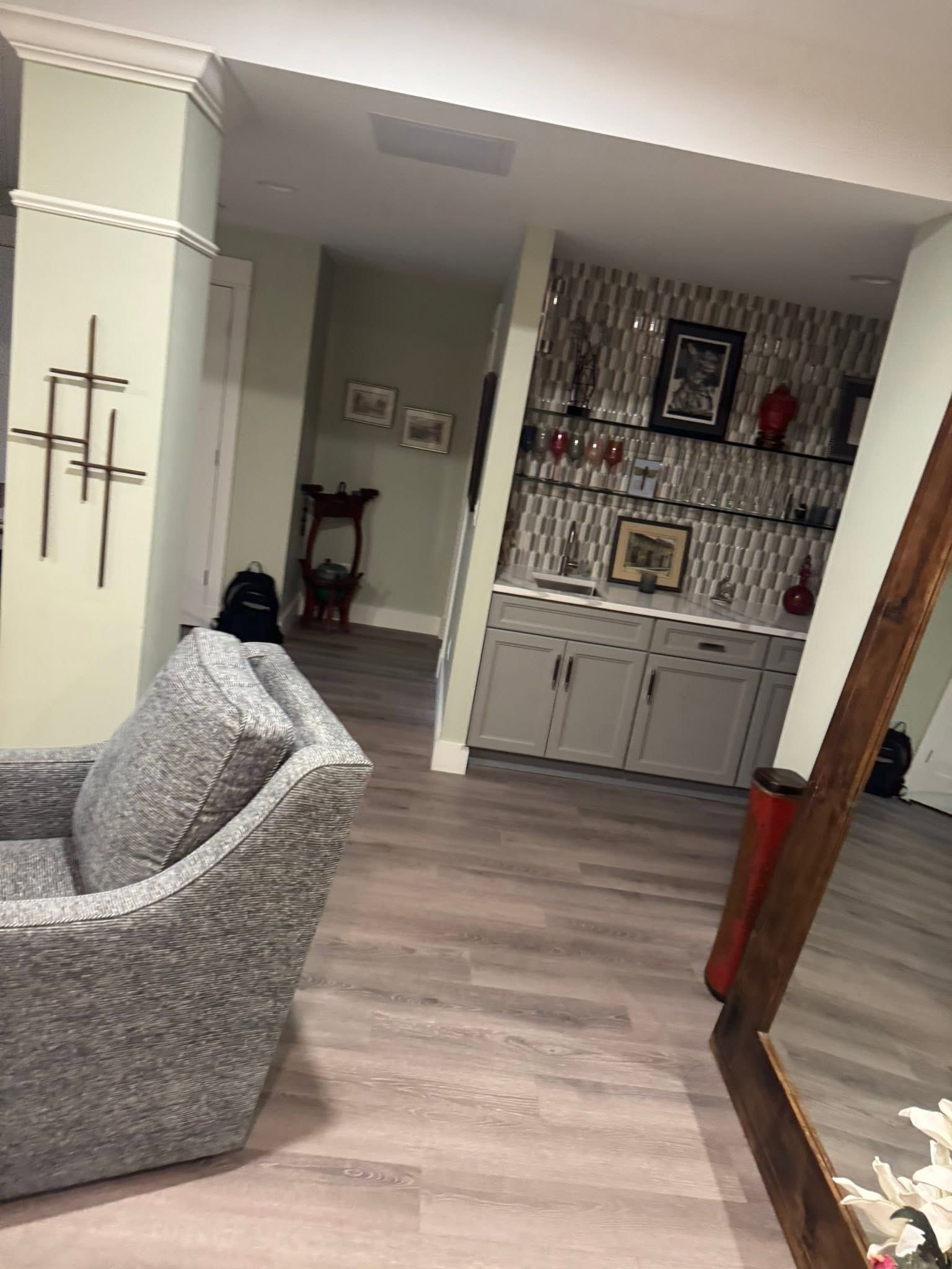 Living room with gray sofa, wood floor, and built-in cabinet with framed photos and decor