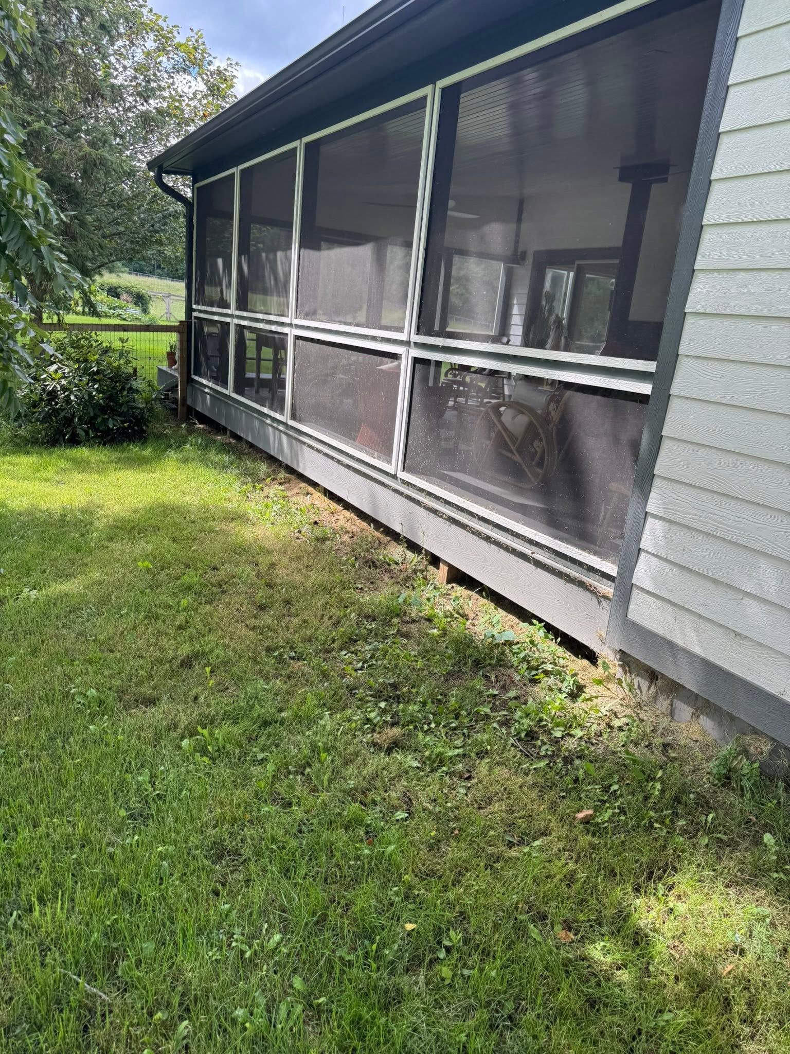 Screened porch on a house with white siding and a grassy yard beside it.