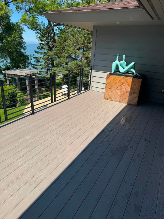 Outdoor deck with a turquoise sculpture on a wood cabinet, overlooking trees and a blue sky.