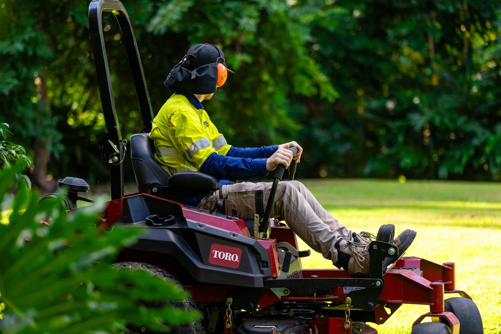 A man is sitting on a lawn mower in a park.