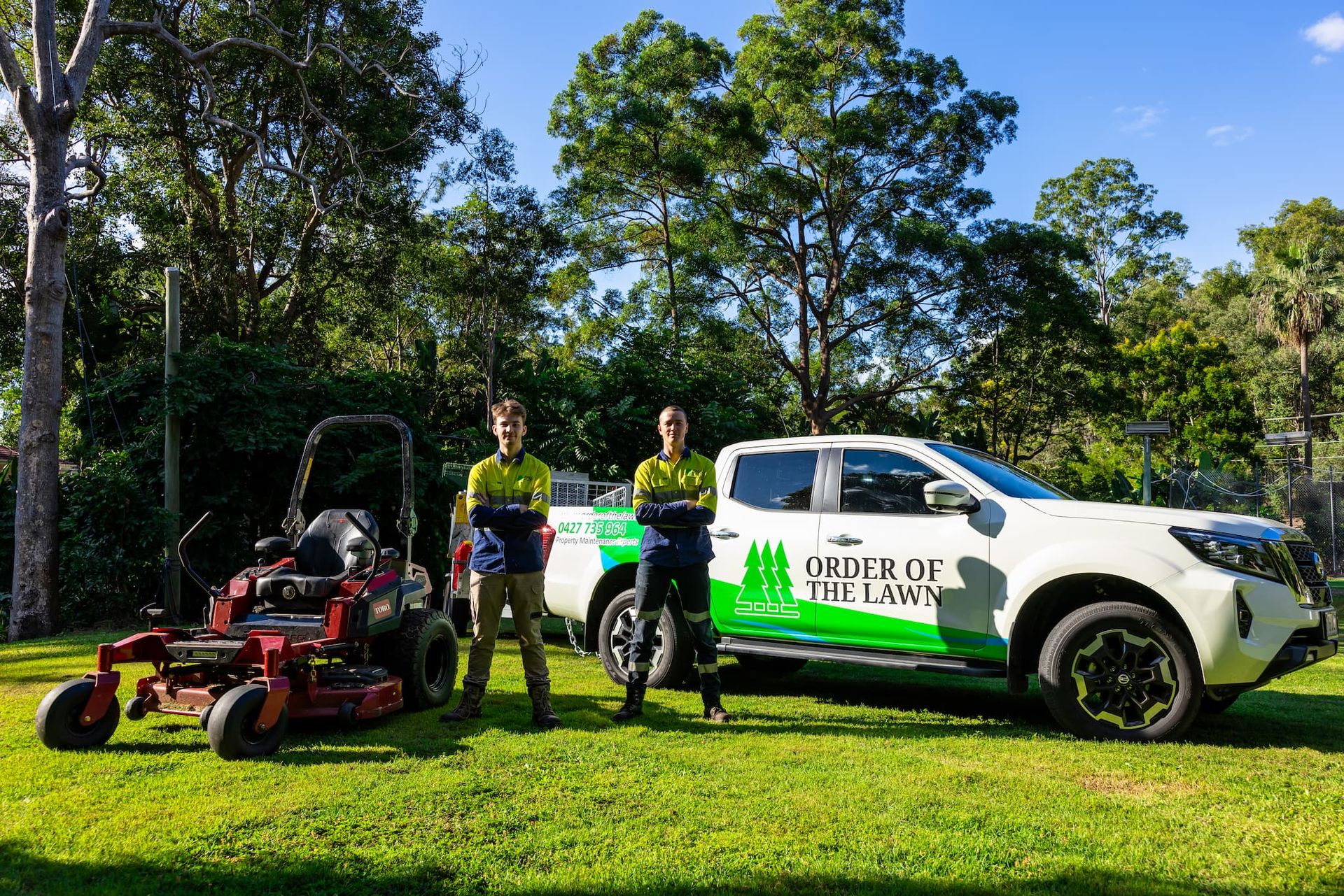 Two men are standing next to a truck and a lawn mower.