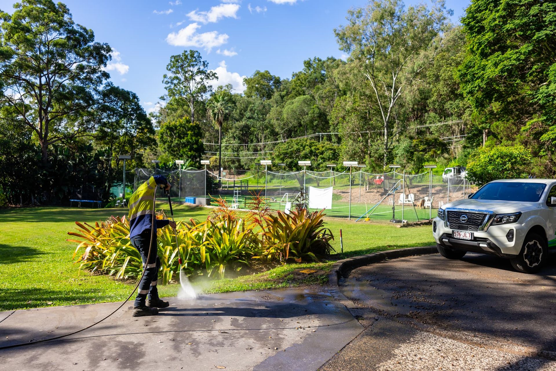 A man is using a high pressure washer to clean a driveway.