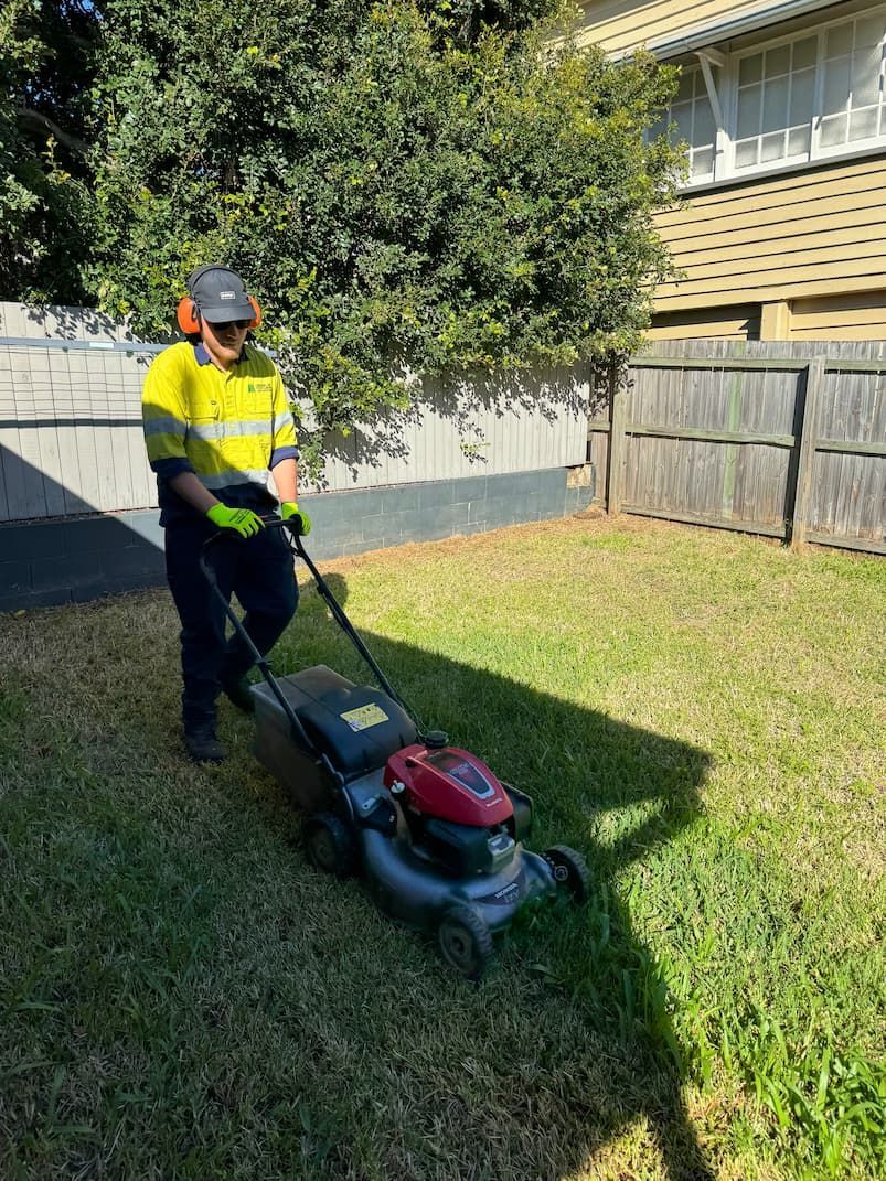 A man is using a lawn mower to cut the grass in a backyard.