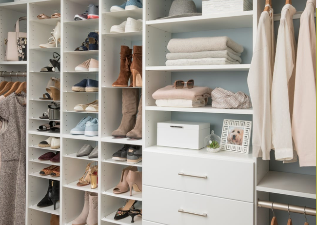 White closet organization with shoe shelves, drawers, and hanging clothes.