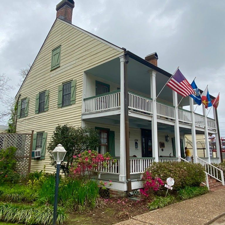 A large house with a porch and flags hanging from it