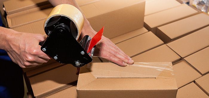 A person is taping a cardboard box with tape.