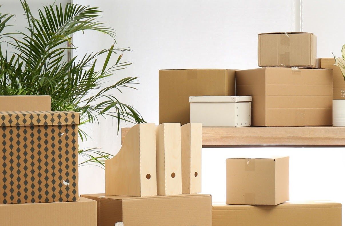 A bunch of cardboard boxes are packed and stacked on top of each other in a room.