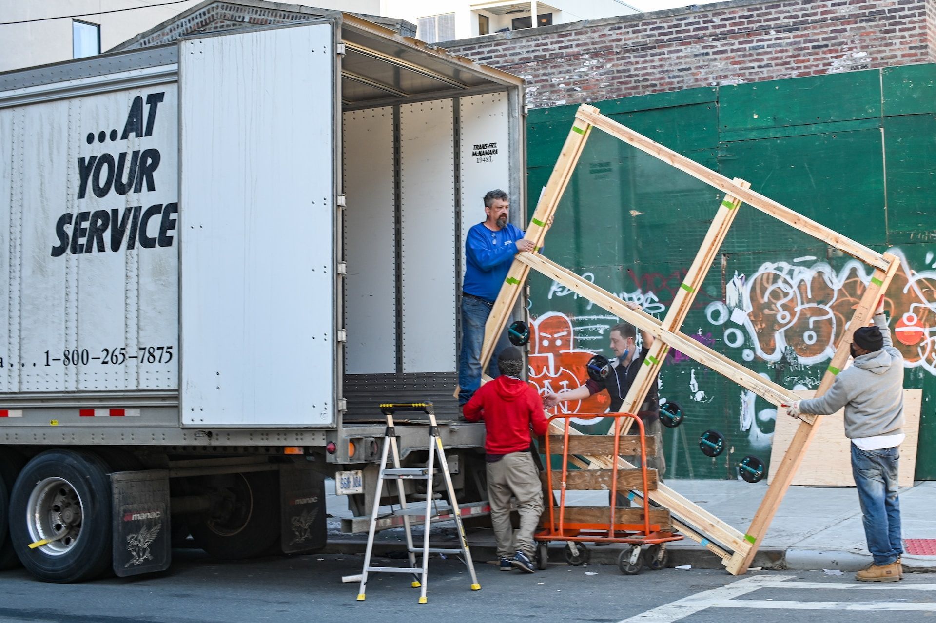Movers loading a large wooden frame onto a truck with