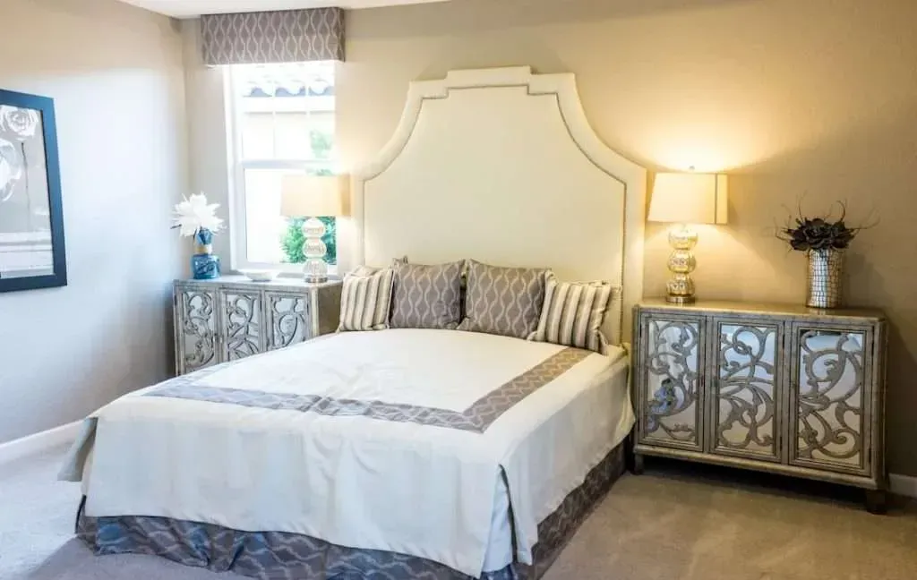 Bedroom with a large bed, two nightstands, a window, and beige walls.