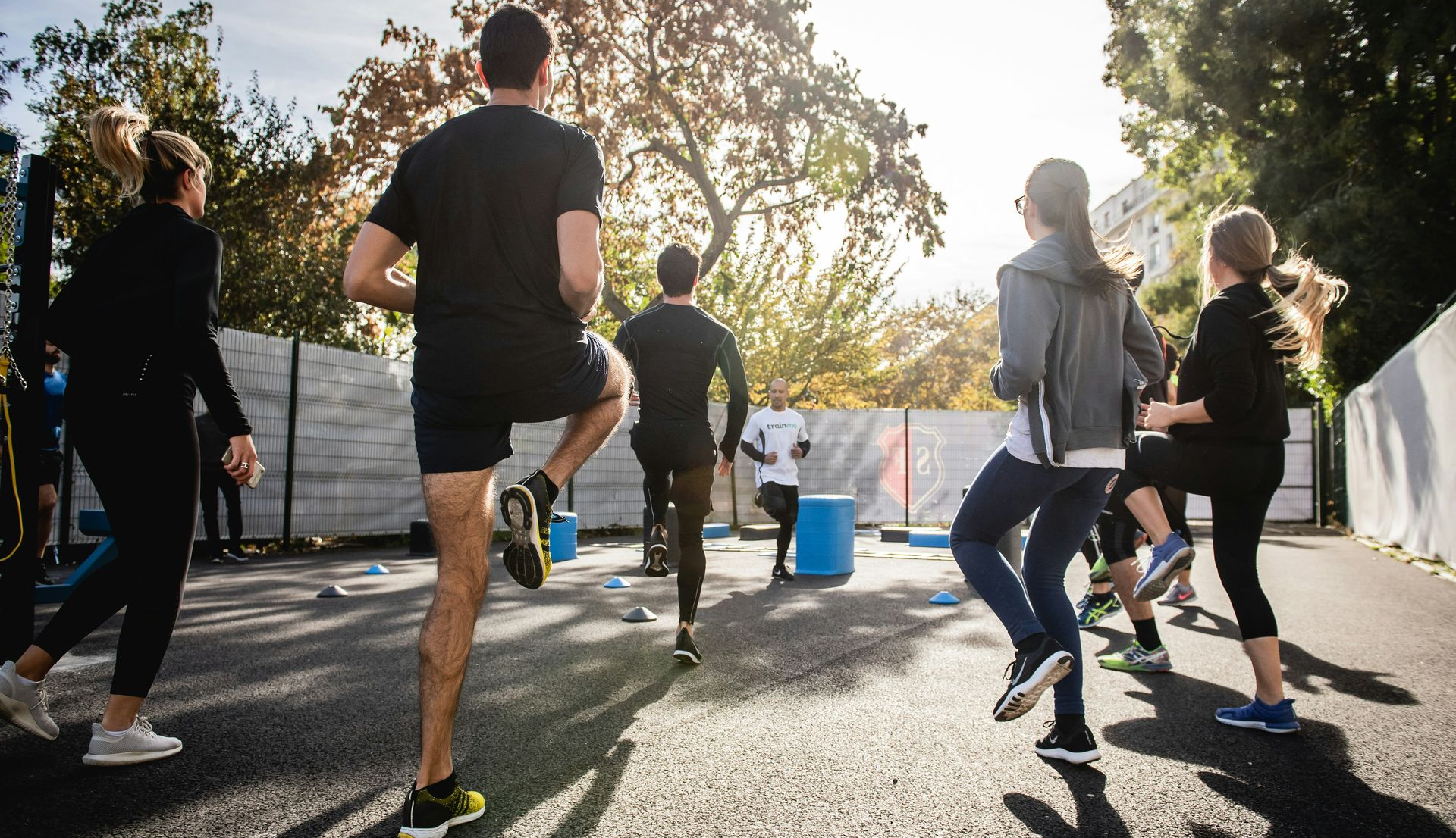 People doing high knees exercise outdoors on a sunny day.
