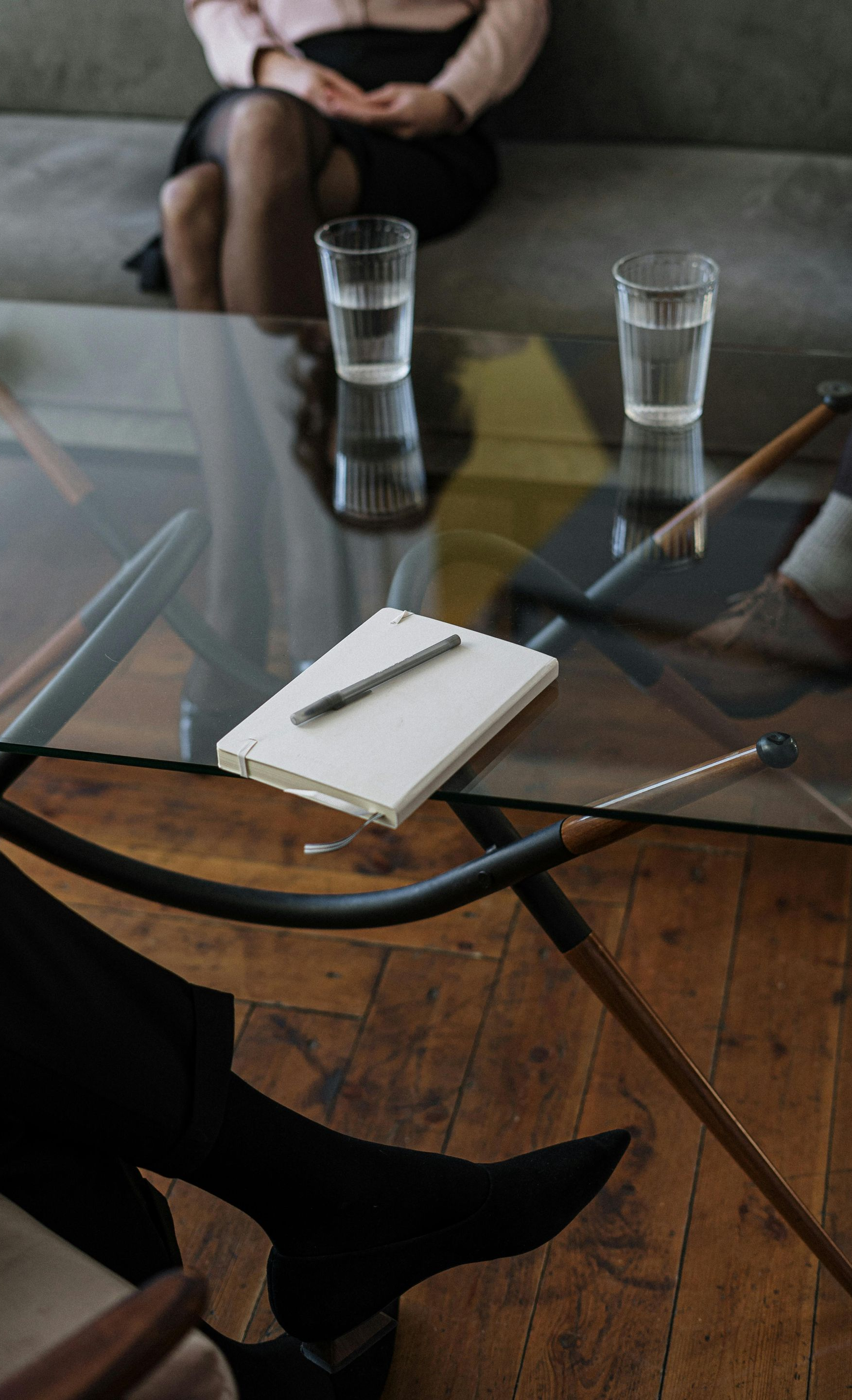 Therapist and patient in session, sitting by a glass table with water and notepad.