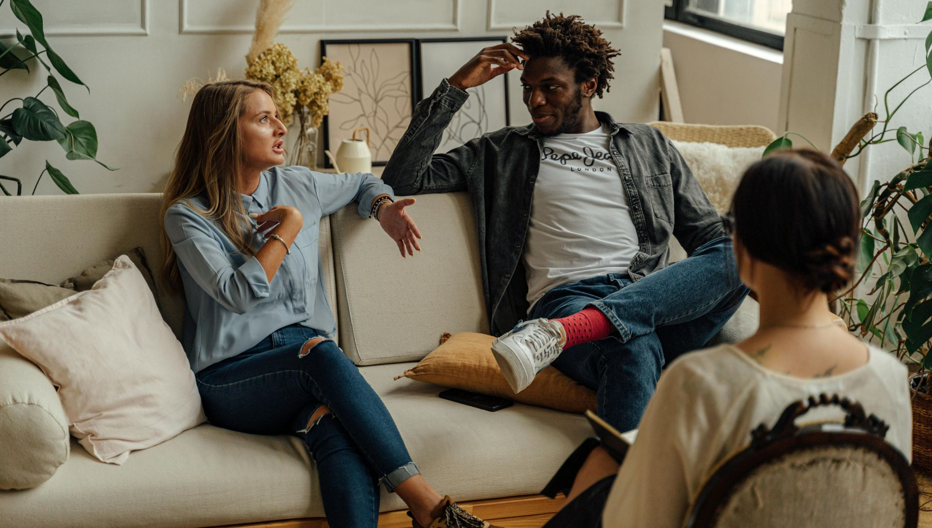 Couple in therapy, arguing on a couch, with a therapist taking notes.