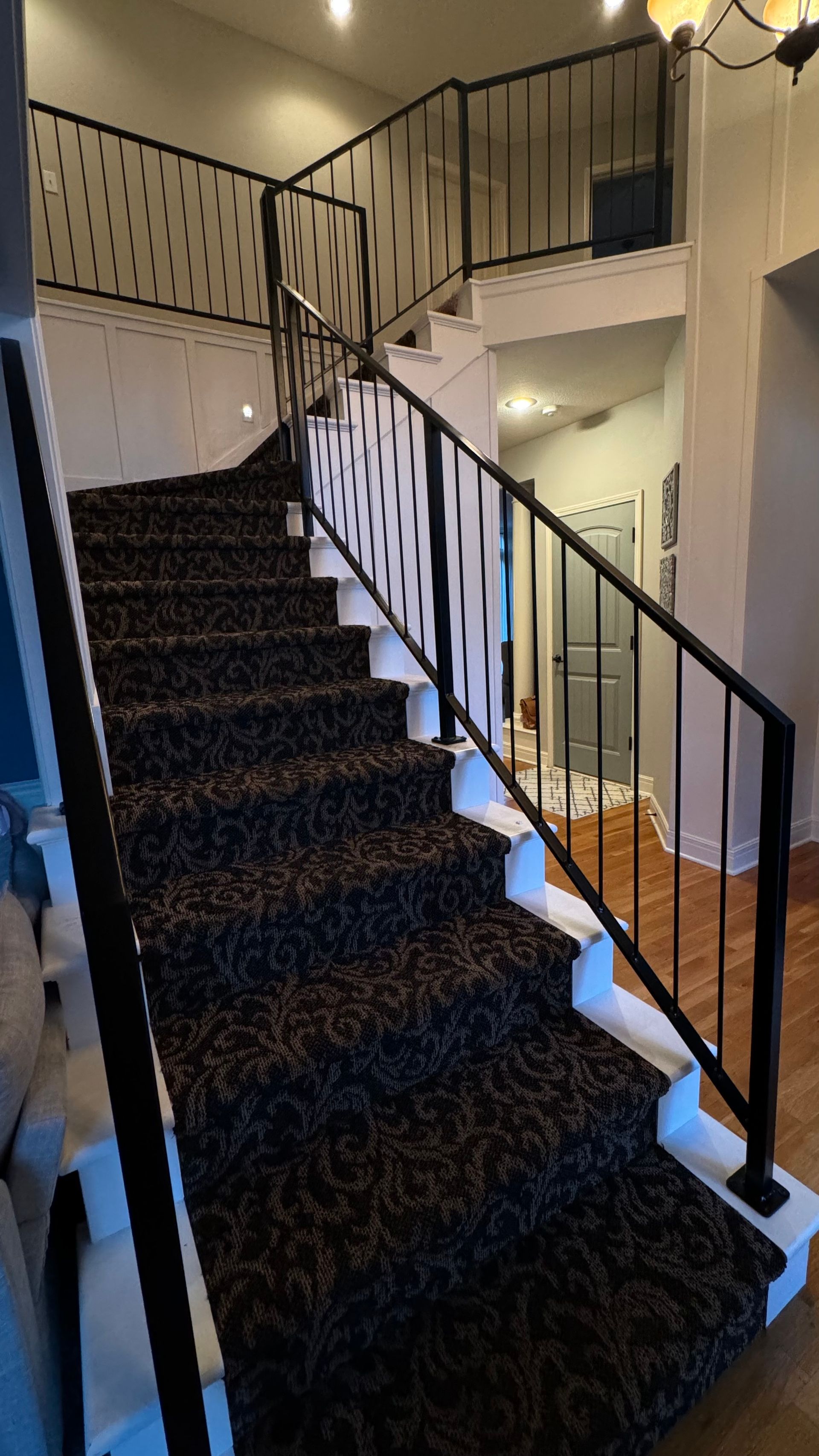 A staircase with a black carpet and a black railing in a house.
