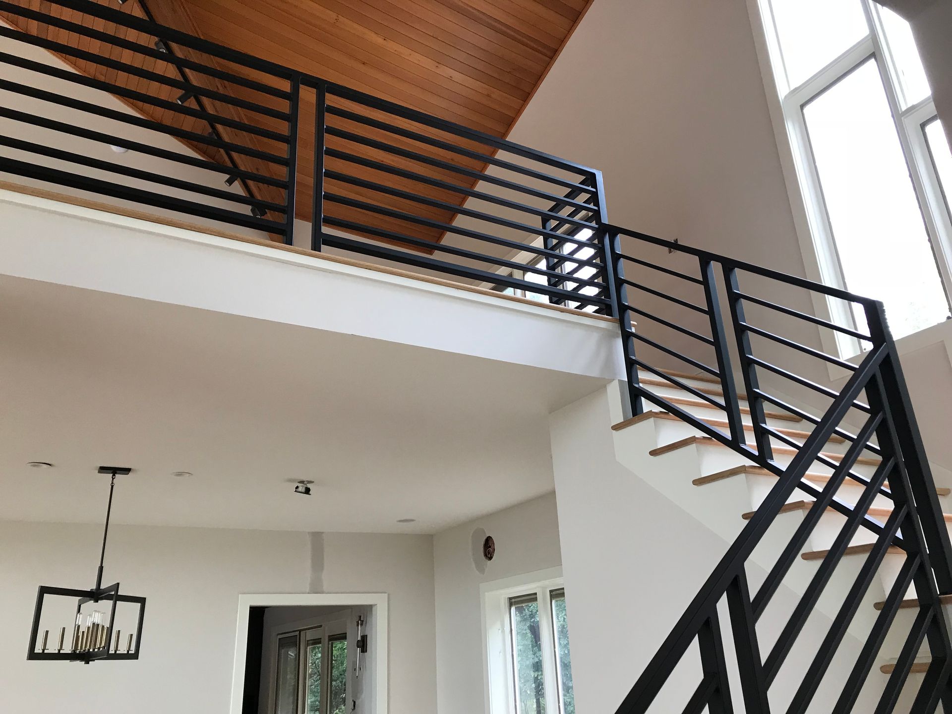 A staircase with a black railing leading to the second floor of a house.