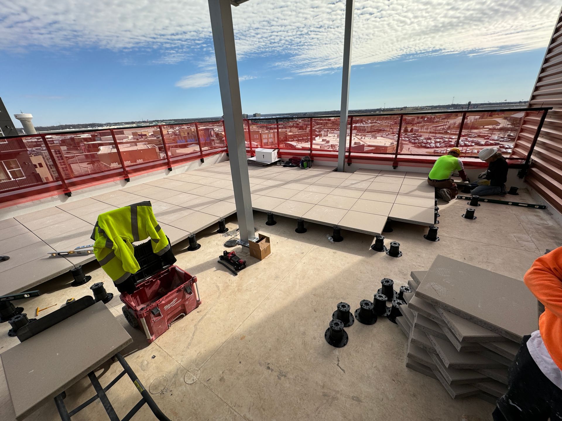 A group of construction workers are working on a rooftop deck.