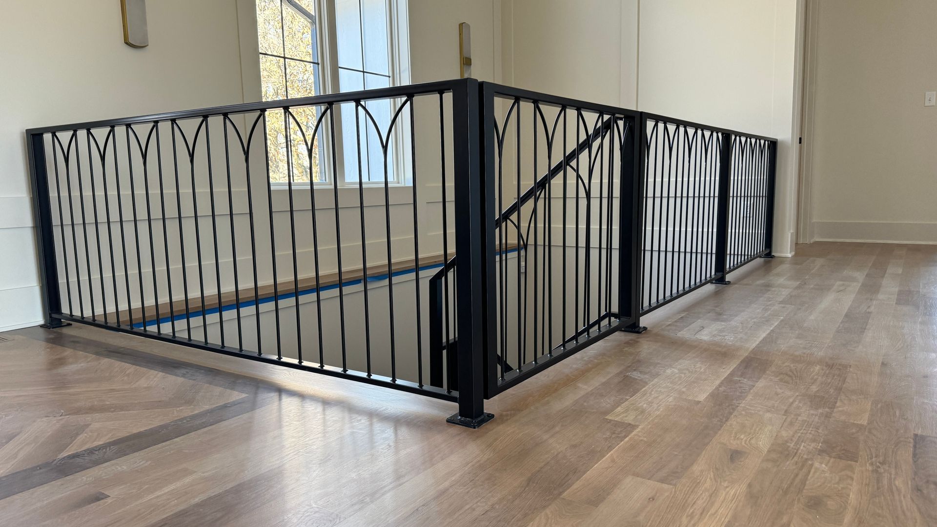 An empty room with a wrought iron railing on the stairs.