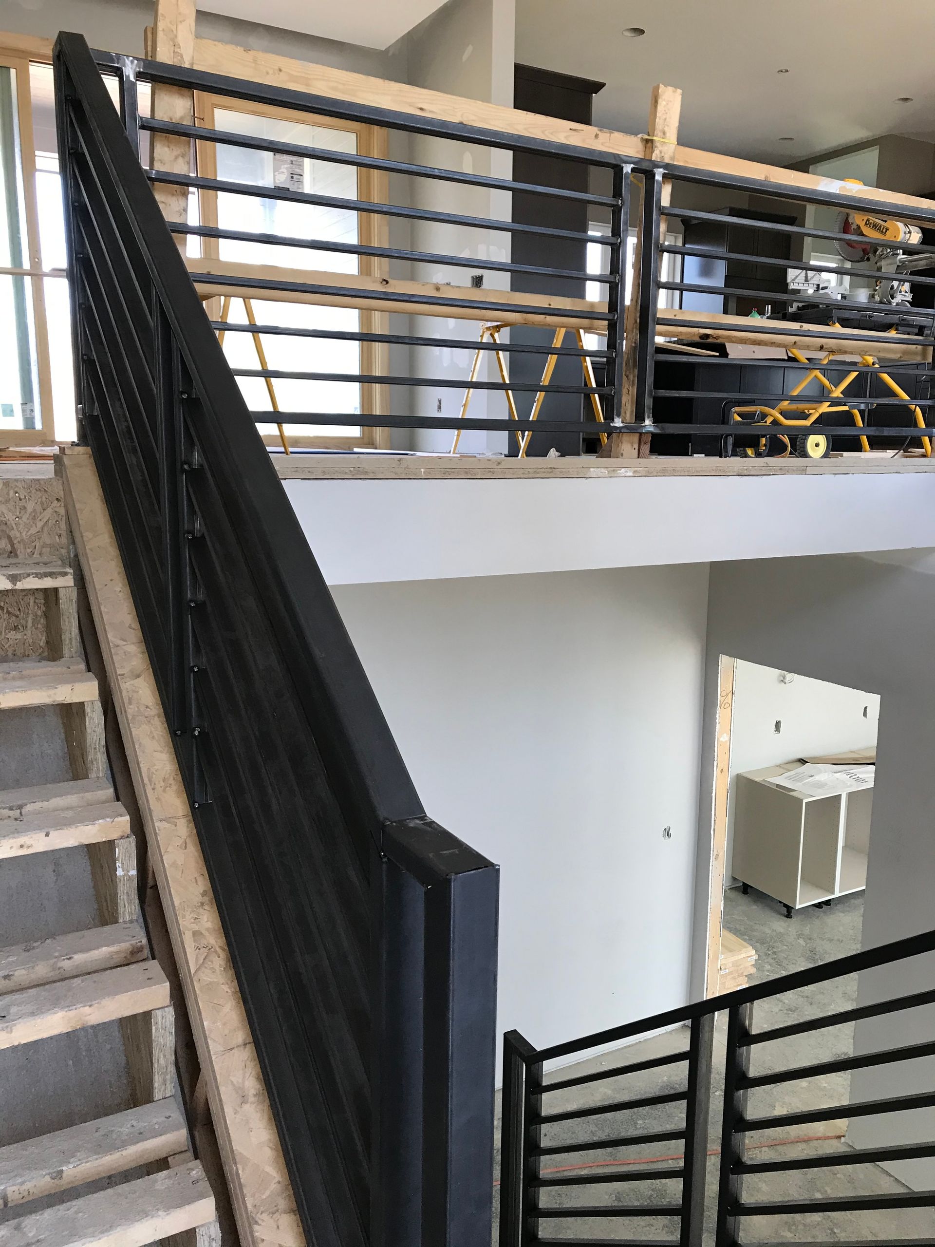 The stairs are being built in a house and the railing is black.