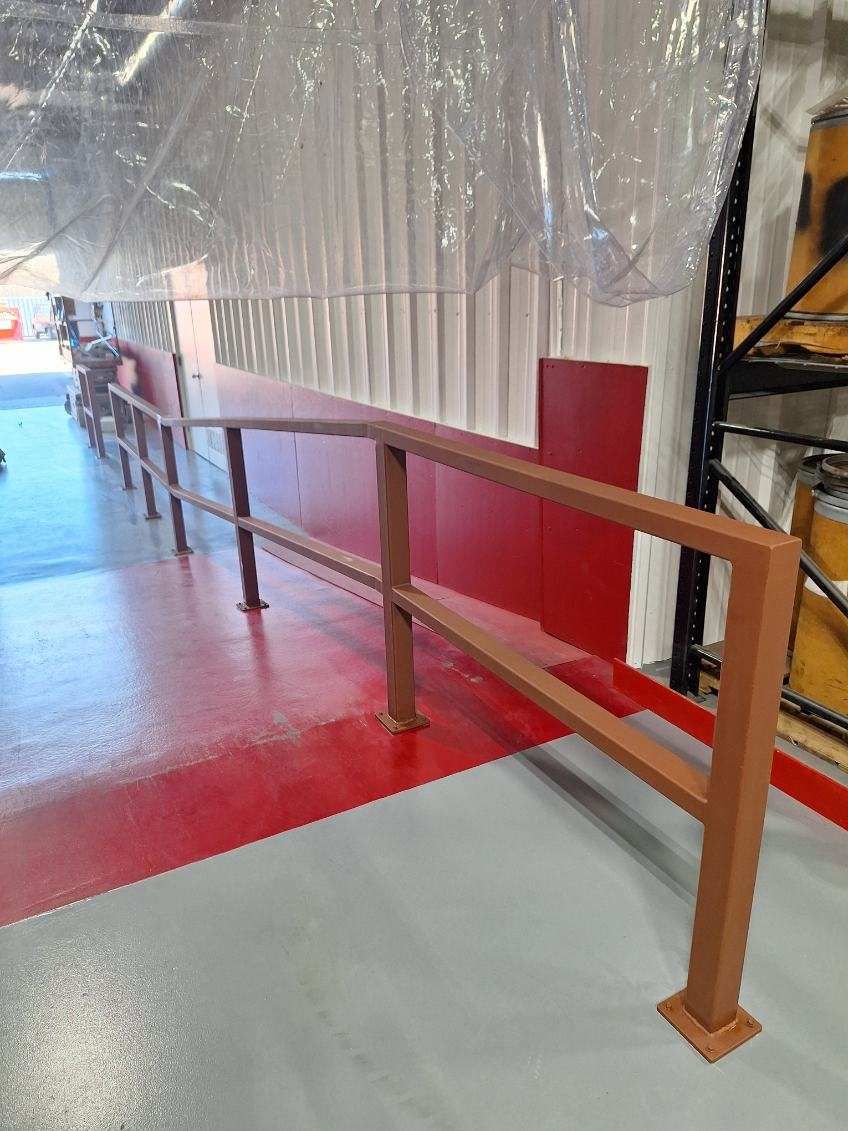 A staircase with a railing in a warehouse with a red wall.