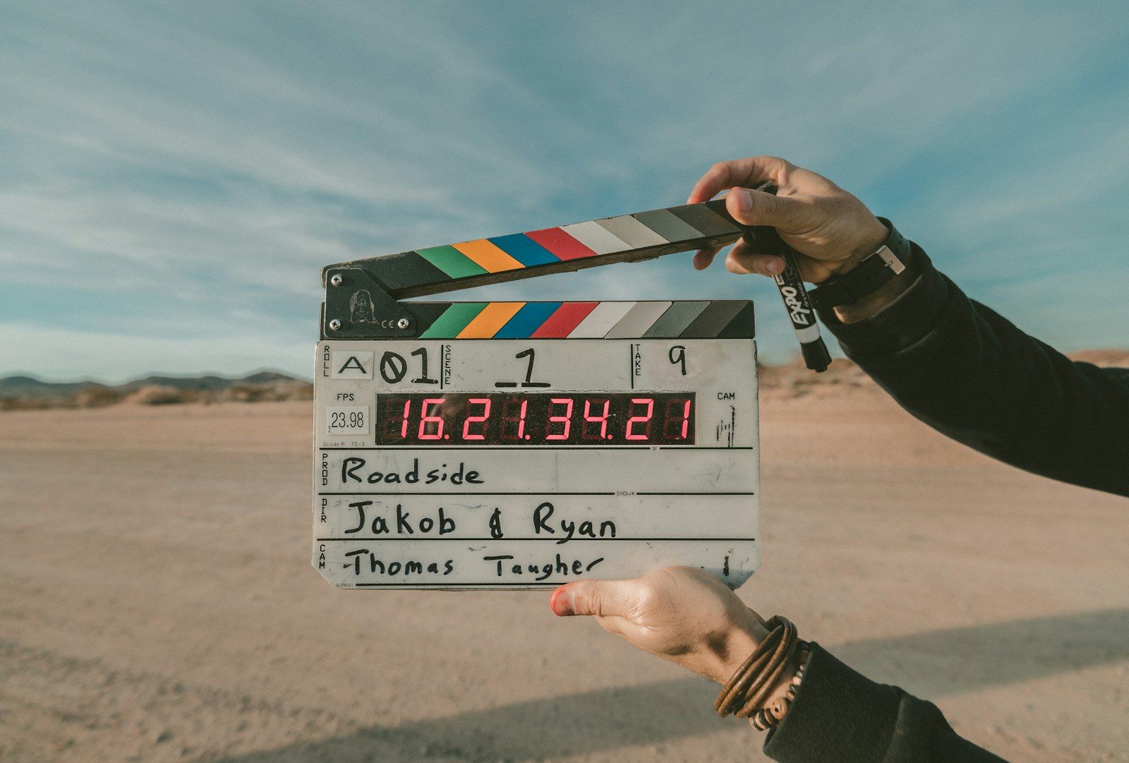 Claquete de cinema segurada diante de uma estrada, no início de uma filmagem