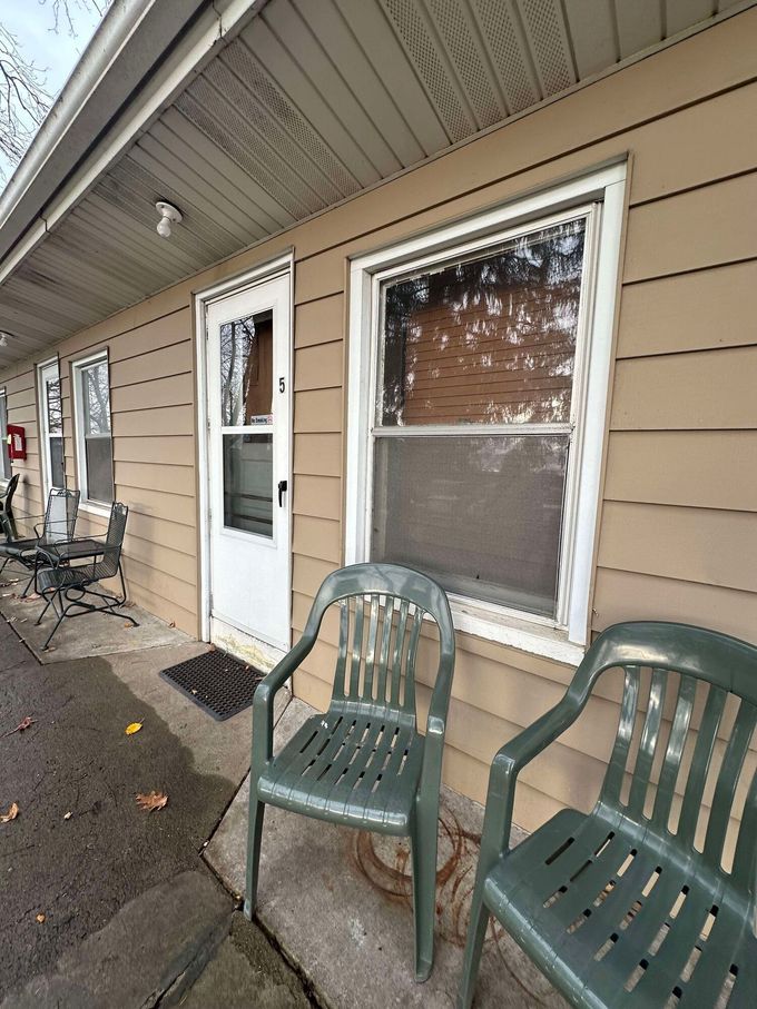 Two green chairs are sitting on the porch of a house.