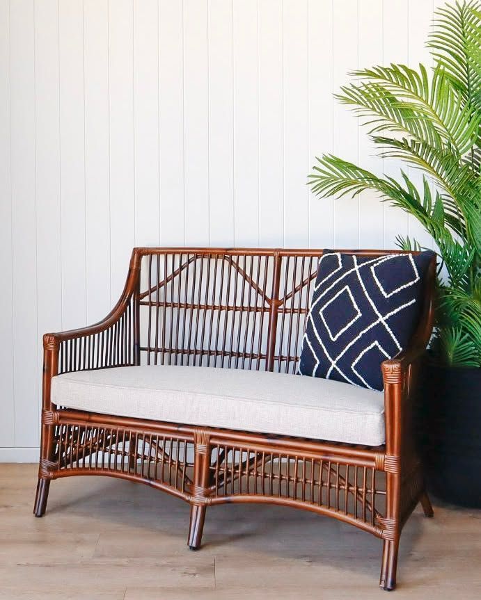 Rattan Loveseat with Cushion, Navy Pillow, and Plant — Tropic Living in Trinity Park, QLD